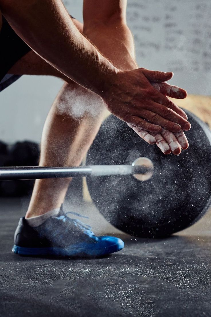 Atleta preparando as mãos com magnésio antes de levantar peso